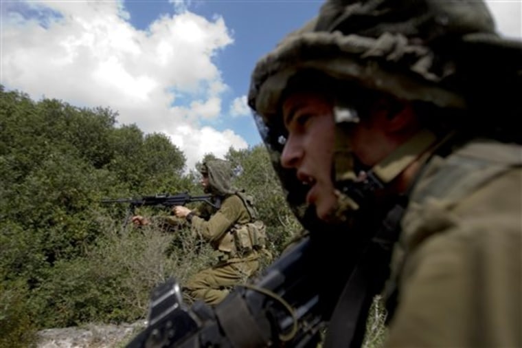 In this photo taken Wednesday, July 21, 2010, Israeli soldiers from the Golani Brigade take position during training in a forest simulating military posts in south Lebanon, at the Elyakim training grounds, northern Israel. With tensions mounting along their shared border, Israel's military says Hezbollah is moving fighters and weapons into the villages of south Lebanon, building up a secret network of arms warehouses, bunkers and command posts in preparation for war. (AP Photo/Ariel Schalit)